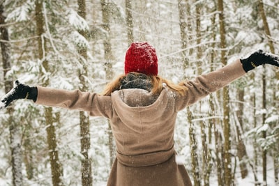 女人穿着连帽衫与雪树附近传播她的手臂
